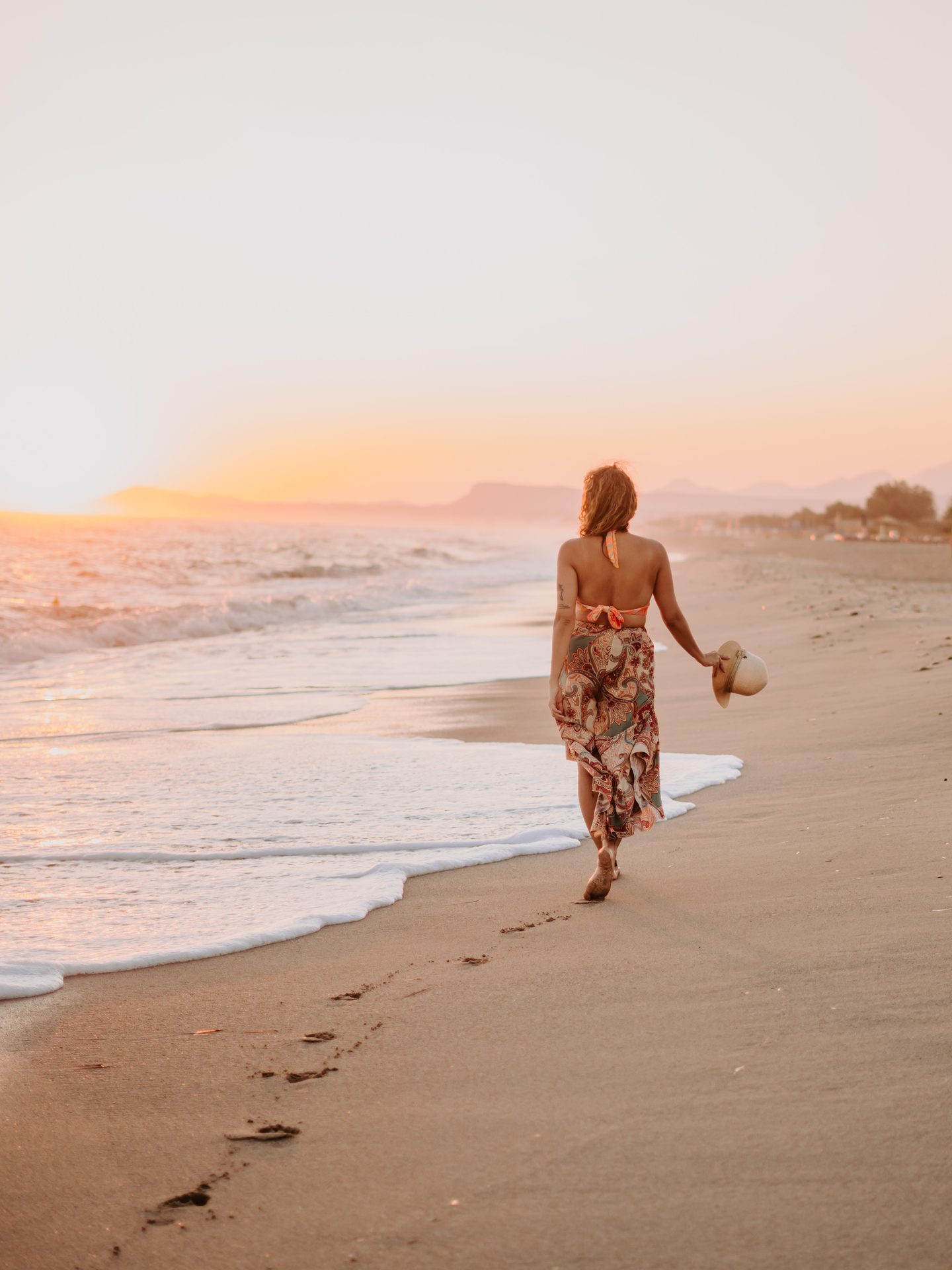 Woman walking on the beach at sunset in Faro, Portugal
